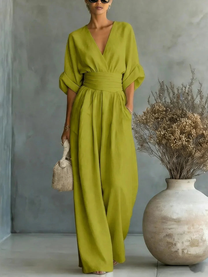 Olive green wide-leg jumpsuit featuring deep V-neck and batwing sleeves
