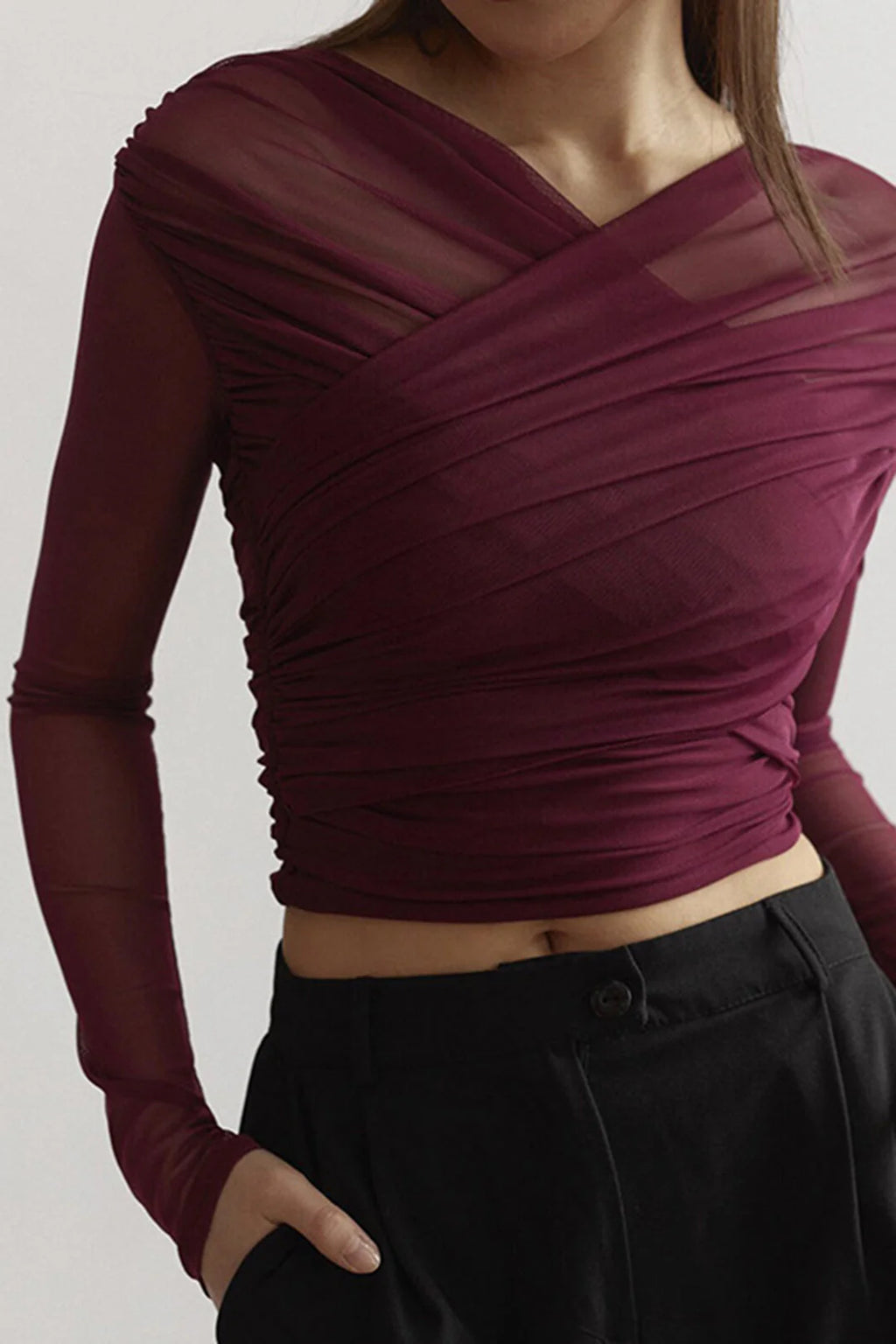 Close-up view of ruched wrap mesh top for women showing diagonal wrap detailing and cropped fit