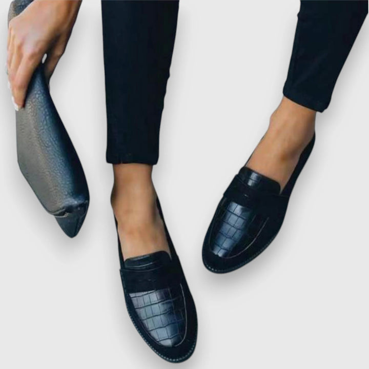 Side angle of women's black loafers showing slip-on design and supportive low sole construction