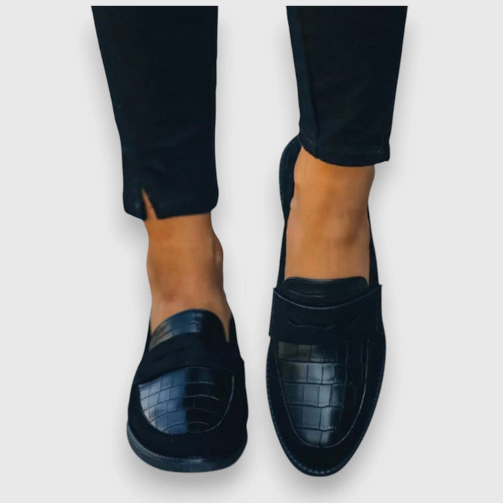 Women's black orthopedic loafers styled with dark trousers, showcasing refined everyday footwear option