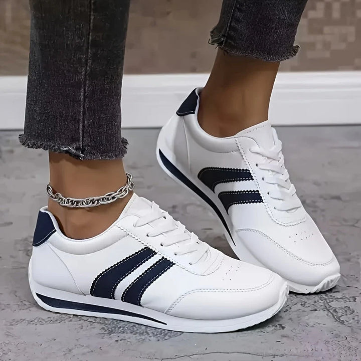 Side profile of white orthopedic trainers with arch support and navy stripe design for everyday wear