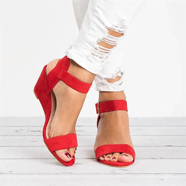 Close-up view of women's black wedge sandals showing buckle closure and wide toe strap detail