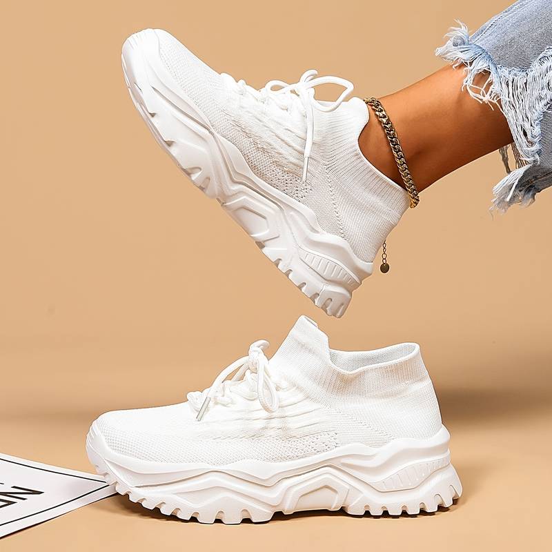 Side angle of white women's orthopedic trainers showing textured mesh construction and supportive lace-up closure for everyday comfort