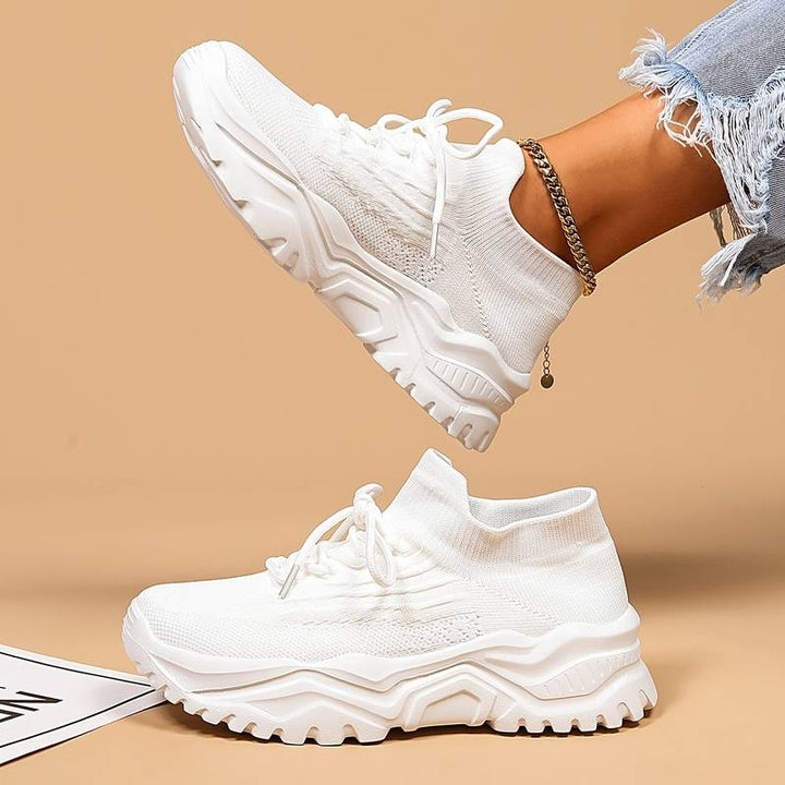 Side angle of white women's orthopedic trainers showing textured mesh construction and supportive lace-up closure for everyday comfort