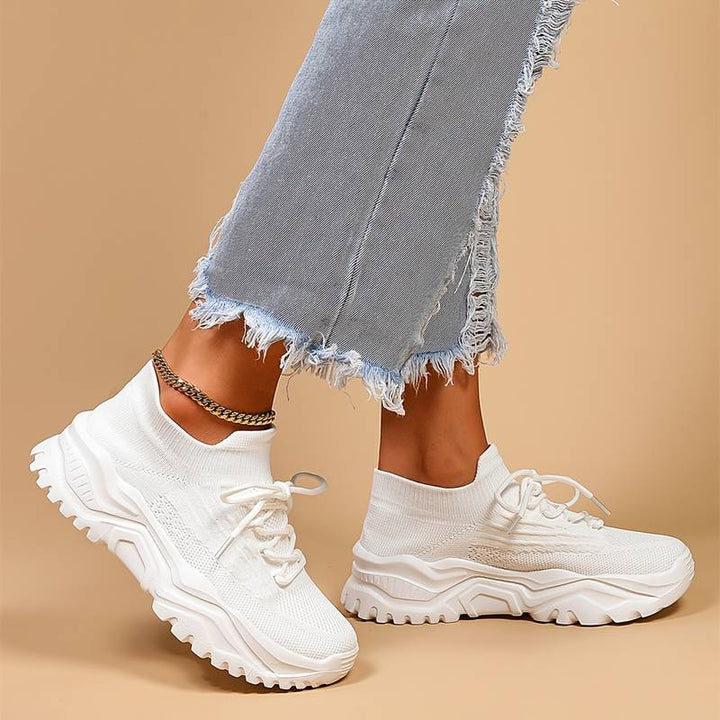 Close-up of white orthopedic shoes for women highlighting cushioned midsole and deep-tread rubber outsole for stability