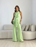 Wide-leg halterneck jumpsuit in pale green with adjustable waist tie and flowing trousers