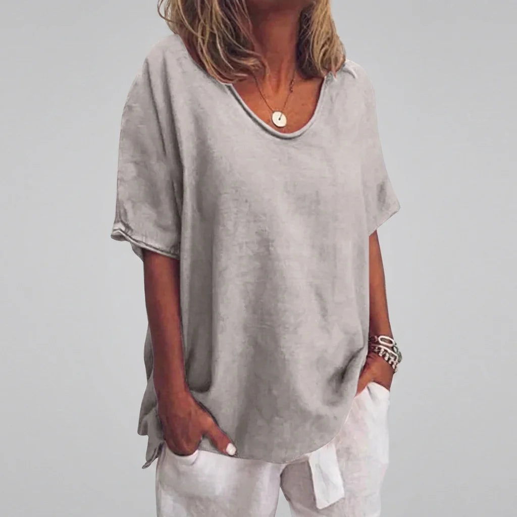 Side angle of women's casual v-neck tee paired with white trousers in beachside setting