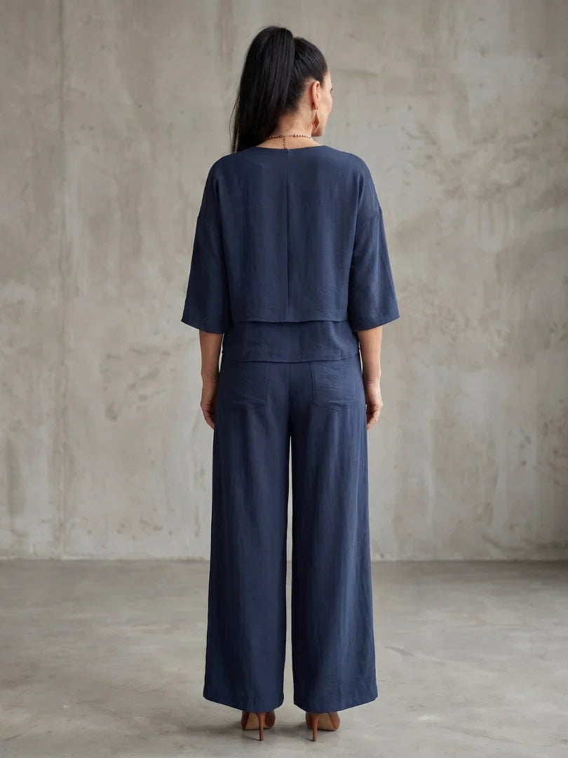 Detail of layered cropped top with elbow sleeves paired with high waisted wide leg pants