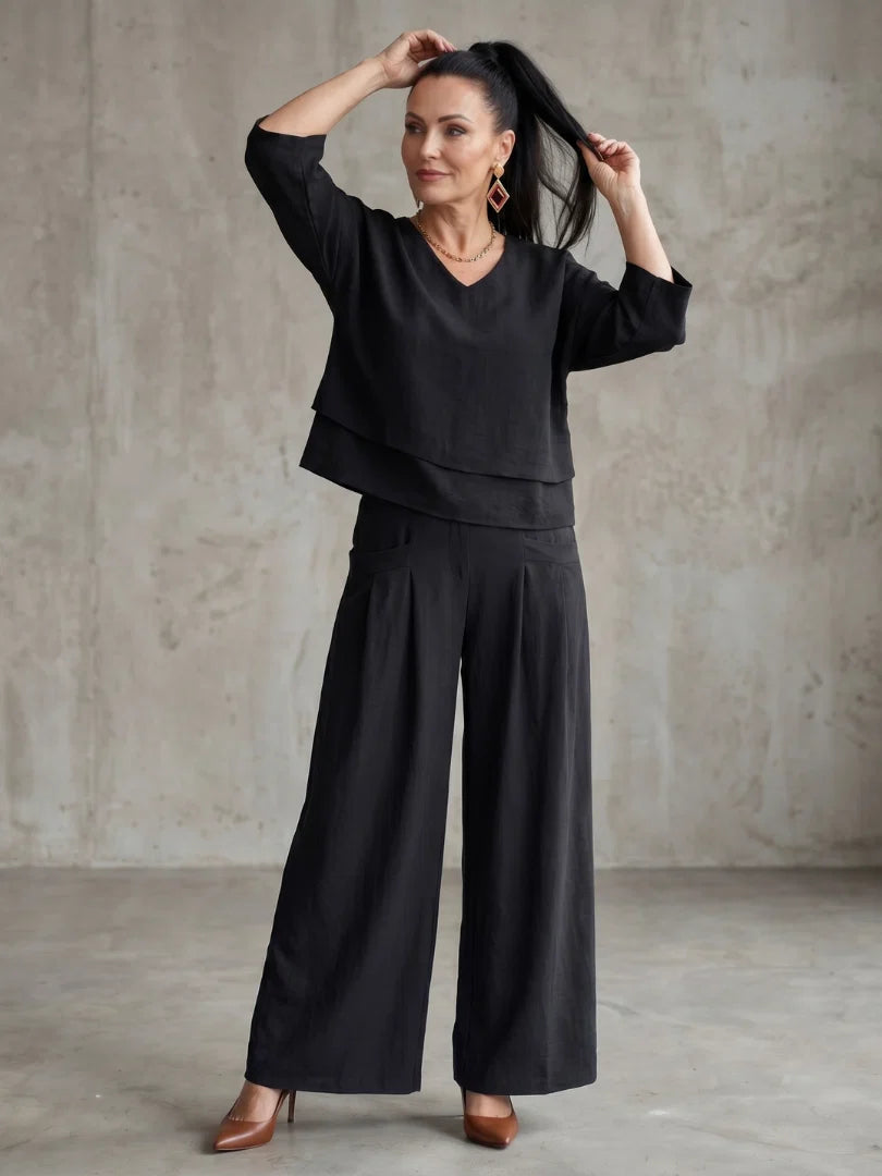 Close up of tiered overlay top construction and pleated wide leg pants detail