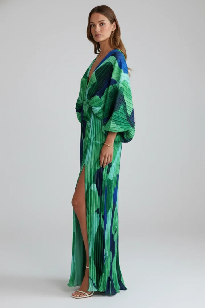 Side view showing slit opening and vertical pleating on full-length printed dress with V-neckline