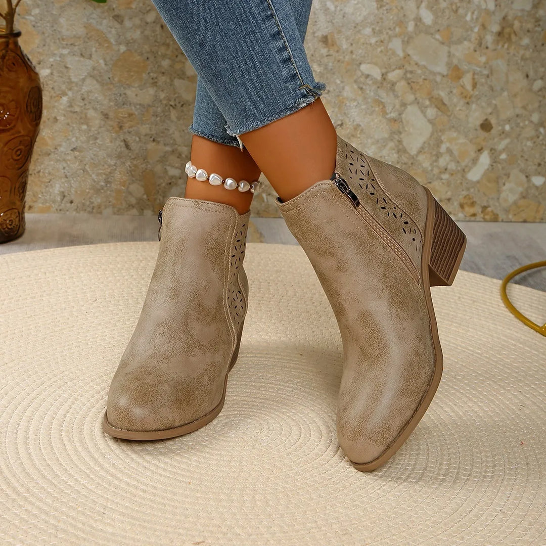 Angled view of women's ankle boots with geometric cutouts and stacked heel detail