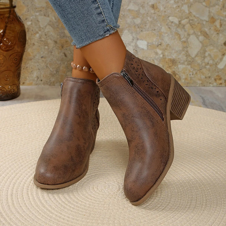 Close-up of stacked block heel construction on women's ankle boots with cutout design