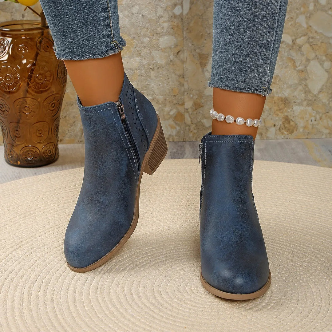 Side view of women's ankle boots showing laser-cut geometric cutout pattern and side zip closure