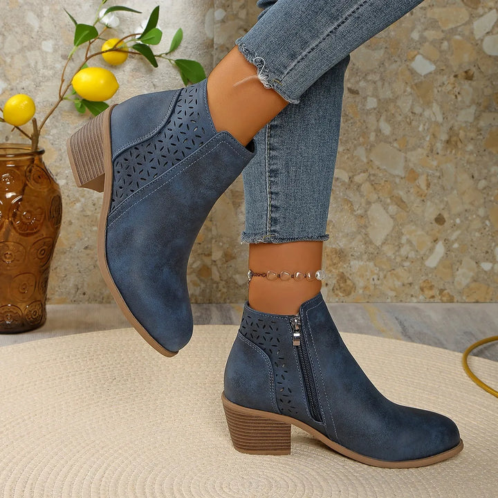 Women's ankle boots cutout detail styled with denim jeans on neutral background