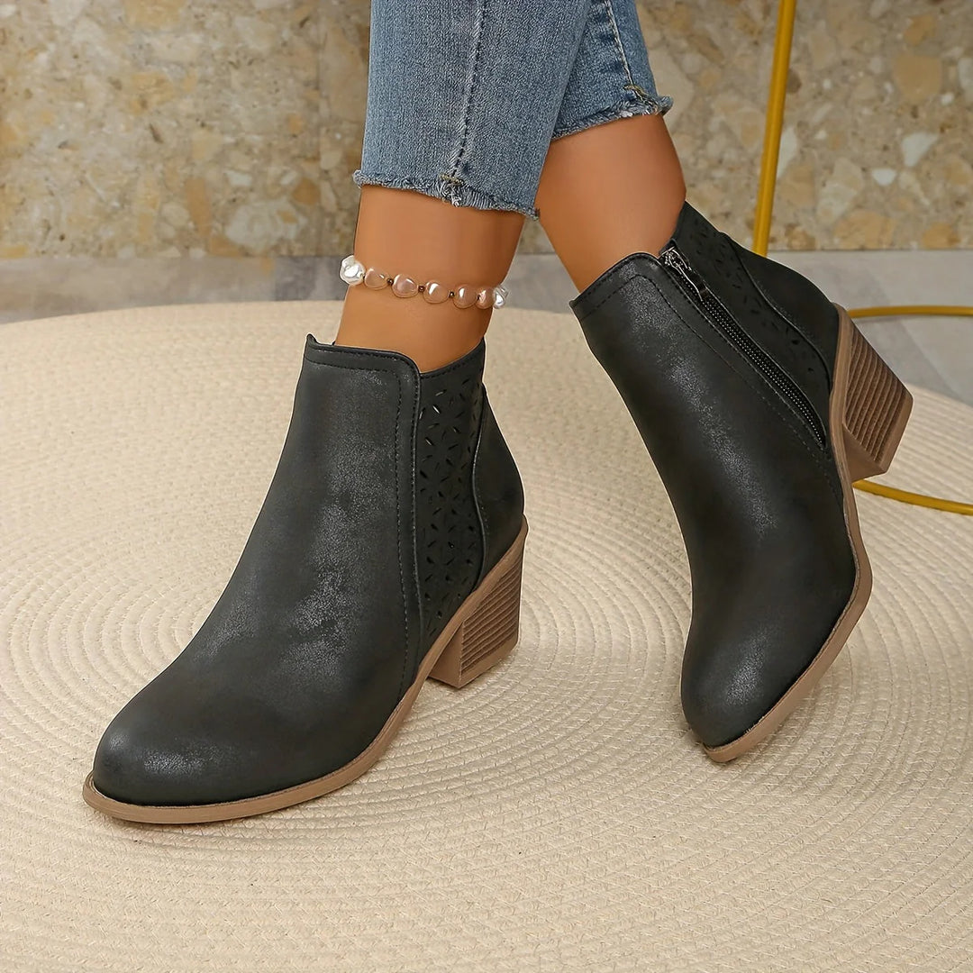 Side profile of women's ankle boots with laser-cut perforations and structured silhouette
