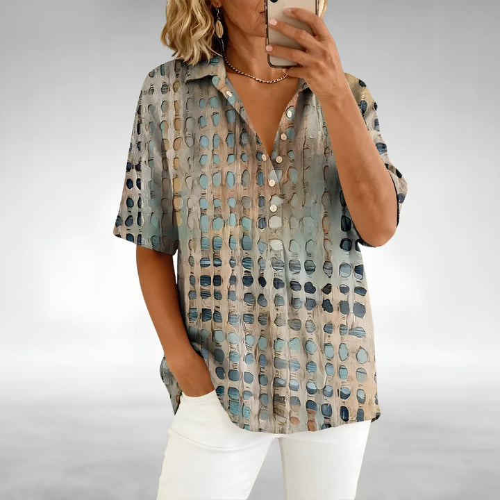 Woman wearing a Relaxed Comfort Top with geometric cut-out pattern and short sleeves paired with white trousers