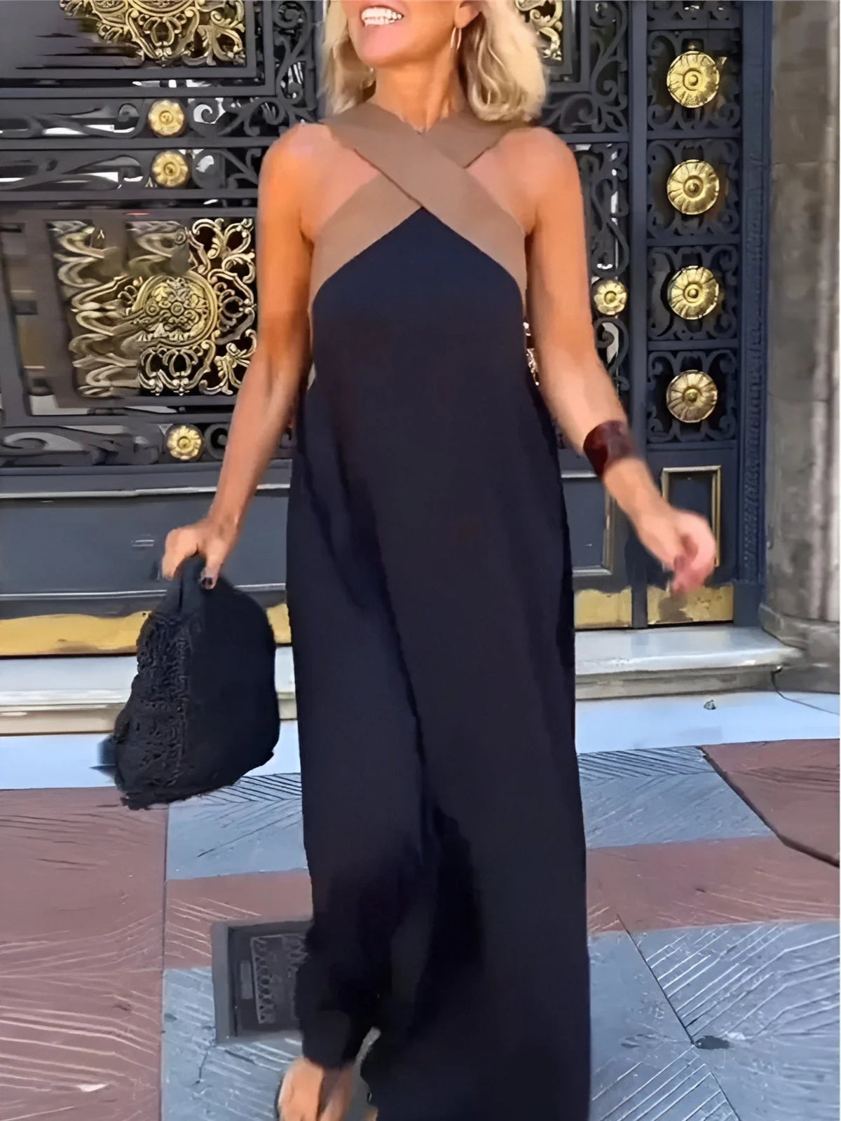 Halterneck maxi dress with crossover bodice detail and flowing black skirt worn outdoors