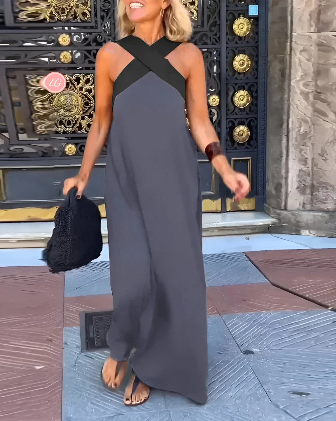 Side angle of sleeveless halterneck maxi dress with floor-length skirt and elegant drape