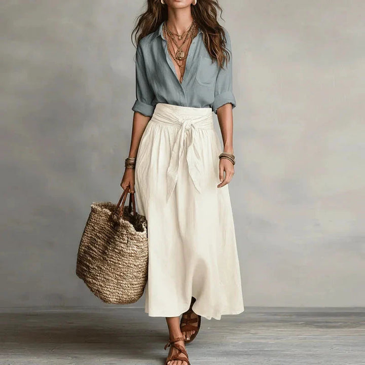 Women's two-piece shirt and skirt set in sage green and cream worn with layered necklaces