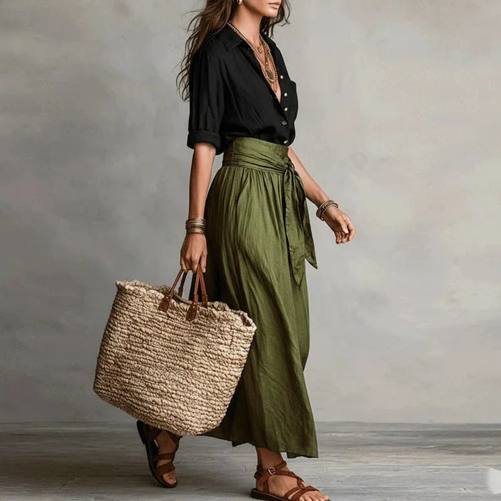 Women's matching shirt and midi skirt ensemble styled with woven bag and sandals