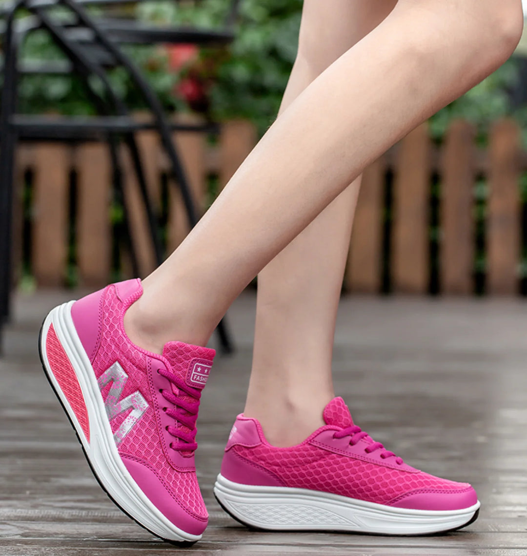 Women's orthopedic sneakers with pink and white curved rocker bottom for natural alignment