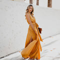 Woman wearing golden yellow sleeveless maxi dress with tie waist and side slit outdoors